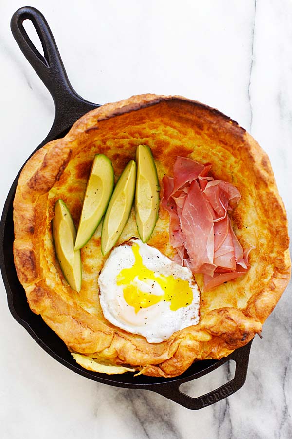 Easy brunch Dutch Baby with egg, prosciutto and avocado in a skillet.