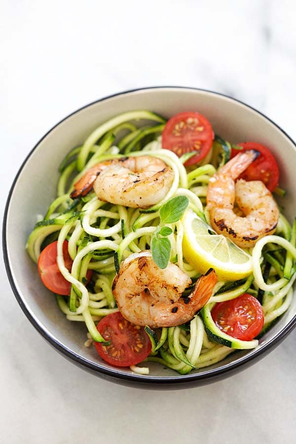 Healthy homemade zucchini noodle salad topped with grilled shrimp and lemon-honey dressing.