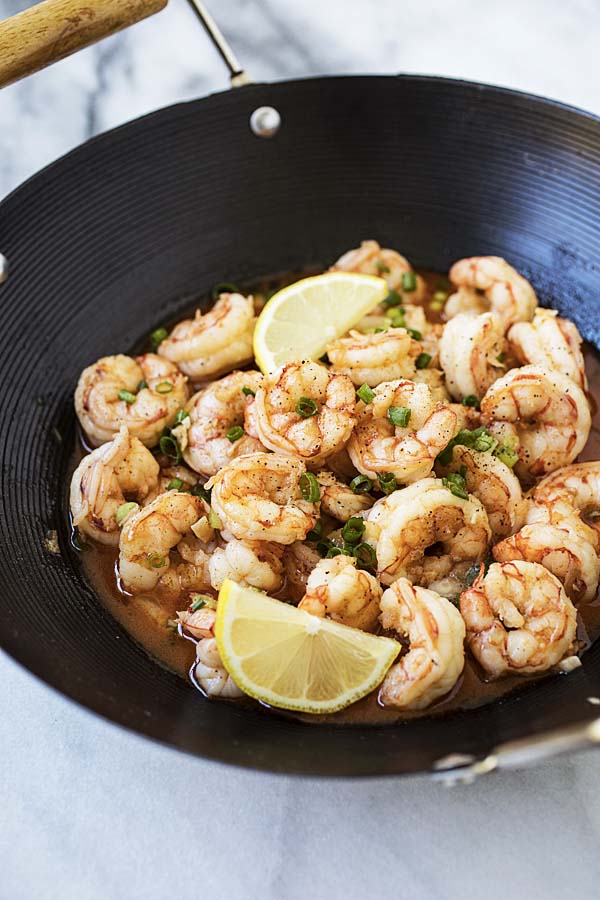 Asian garlic butter shrimp topped with lemon wedges.