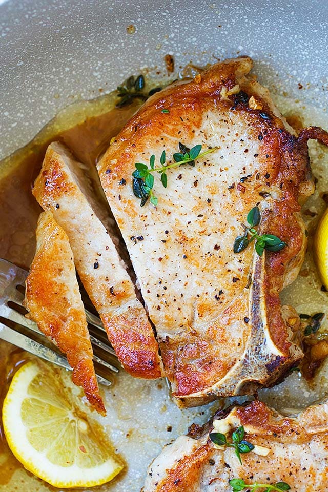 Sliced pork chops with garlic butter sauce in a skillet.