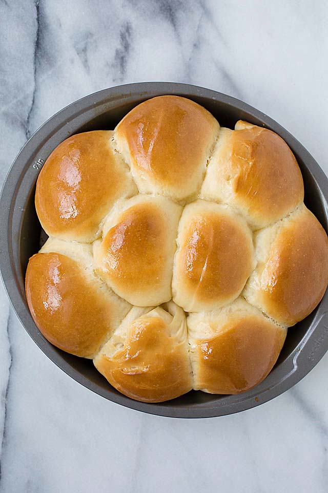 Top down shot of golden dinner rolls in a baking pan.