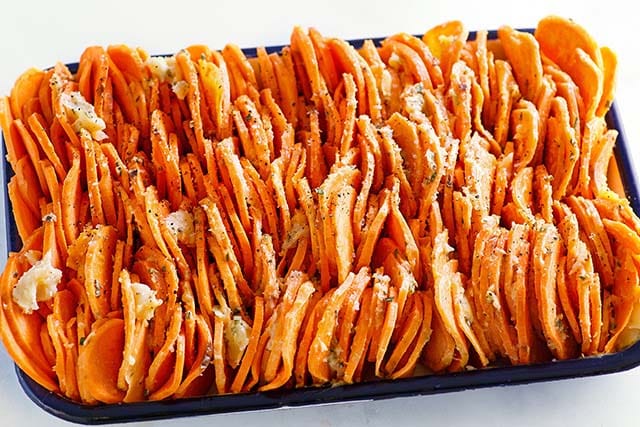 Raw slices of sweet potato chips on a baking tray.