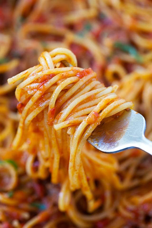 A fork with spaghetti and red meat sauce.