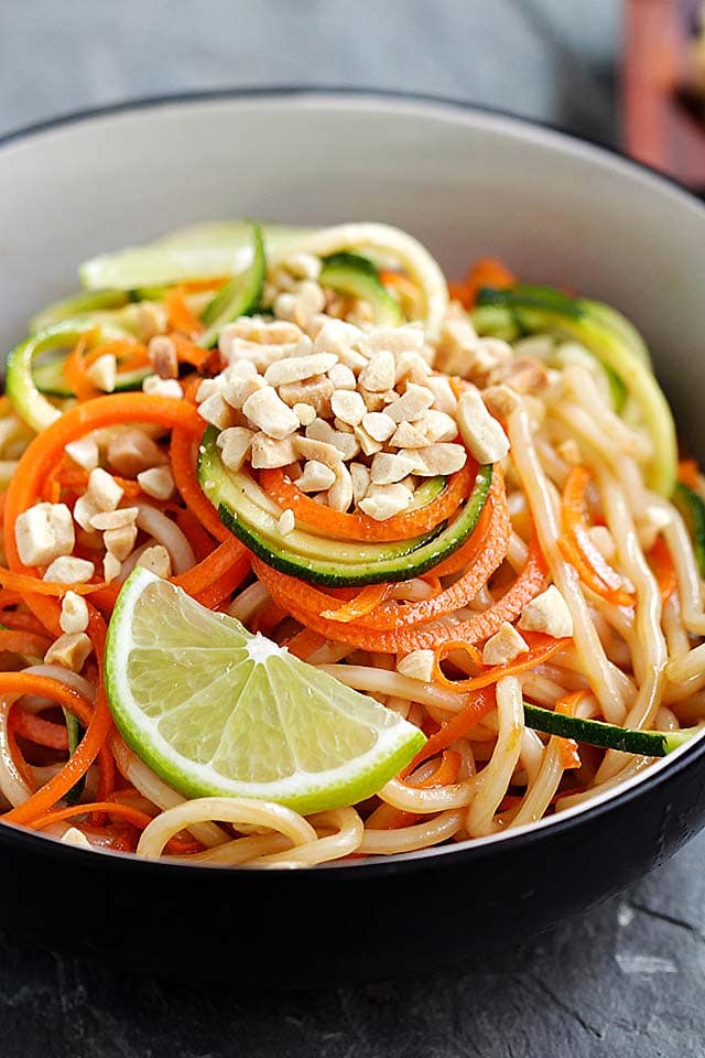 Close up shot of Thai peanut zucchini noodles served in a bowl, topped with crushed peanuts.