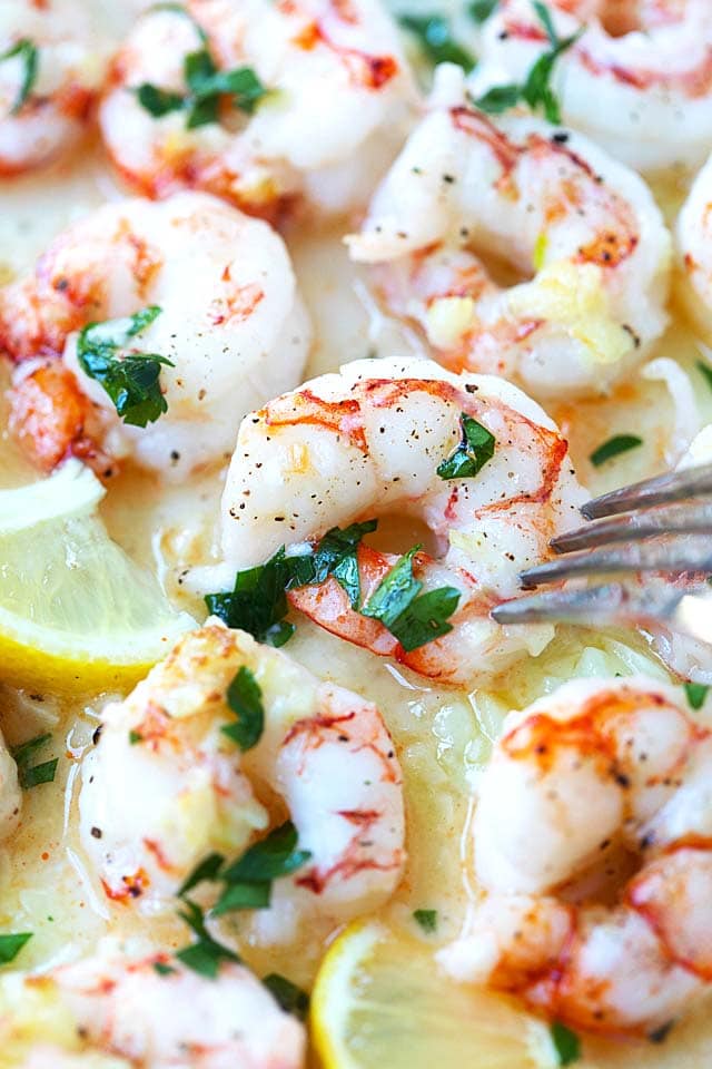 Jumbo shrimp broiled with garlic butter, served with a fork.