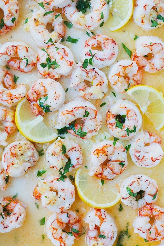 Garlic butter shrimp served with lemon wedges.