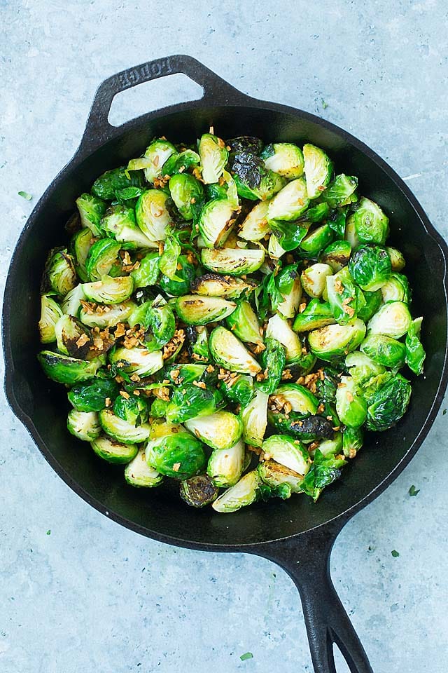 Sauteed Brussels Sprouts in a cast-iron skillet with crispy garlic.