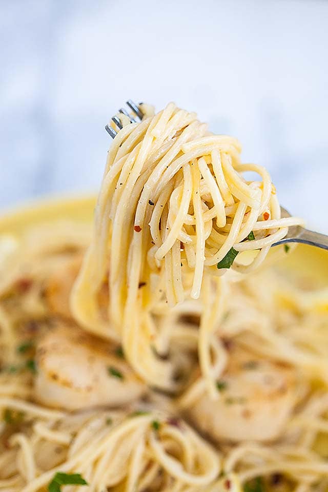 Delicious homemade white wine spaghetti pasta with creamy scallops recipe on a fork. 