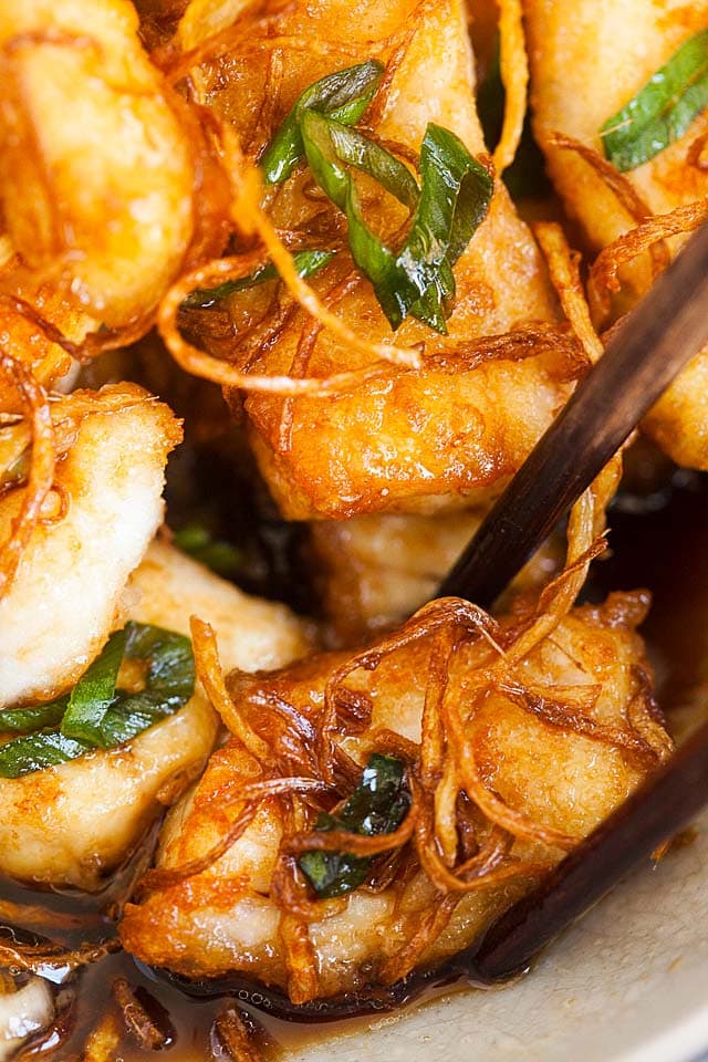 A pair of chopsticks picking up a piece of halibut fish fillet.