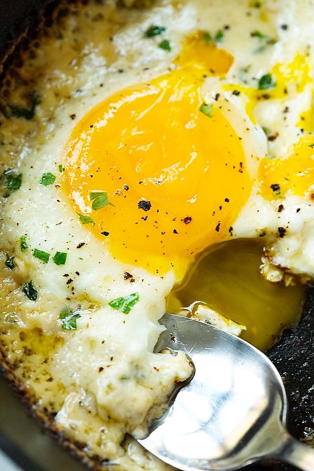 Parmesan eggs with runny egg yolk in a skillet.