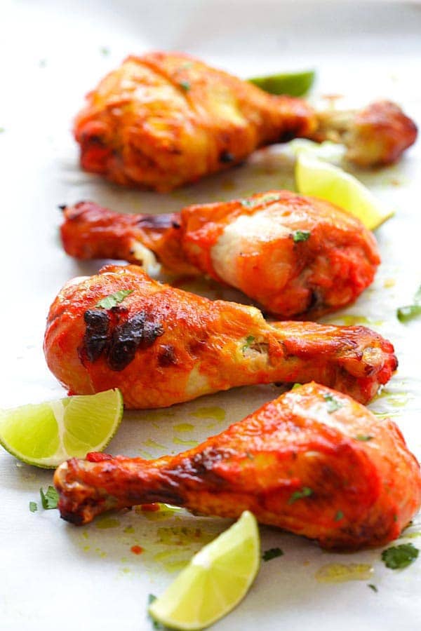 Authentic tandoori chicken recipe served with limes and cilantro.