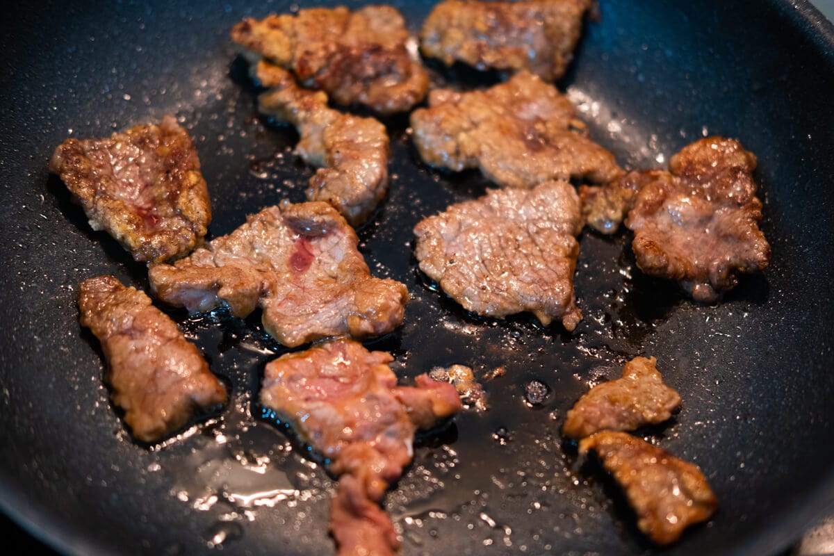 Deep frying the beef in a pan until golden brown. 