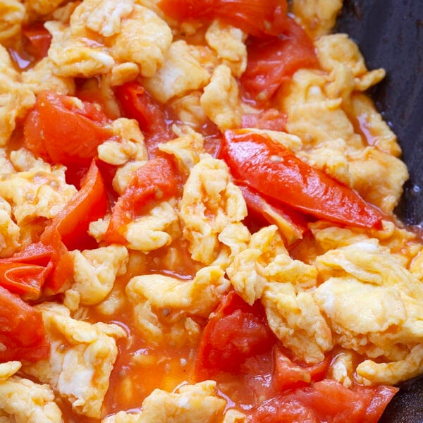 Tomato and eggs stir fried in a skillet.