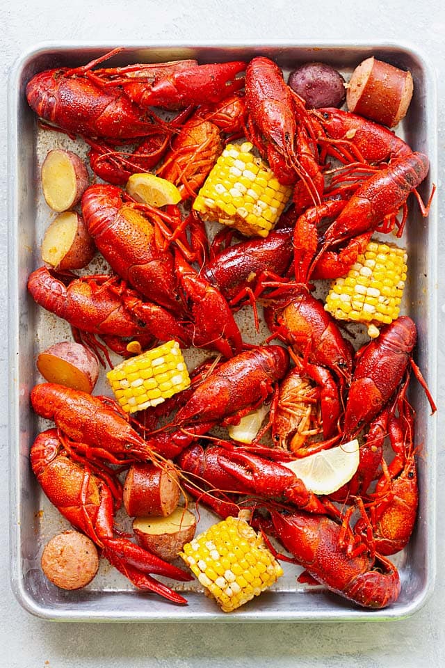 Fully cooked crawfish boil with corn, smoked sausage, and red potatoes on a serving tray.