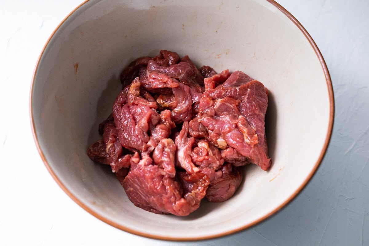 Marinating beef slices in a bowl with marinade ingredients.  