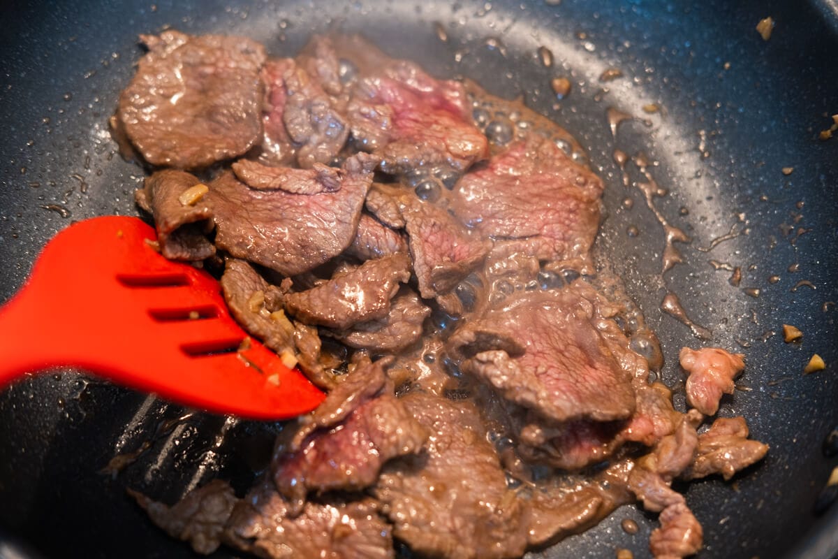 Stir fry the marinated beef slices in a pan. 