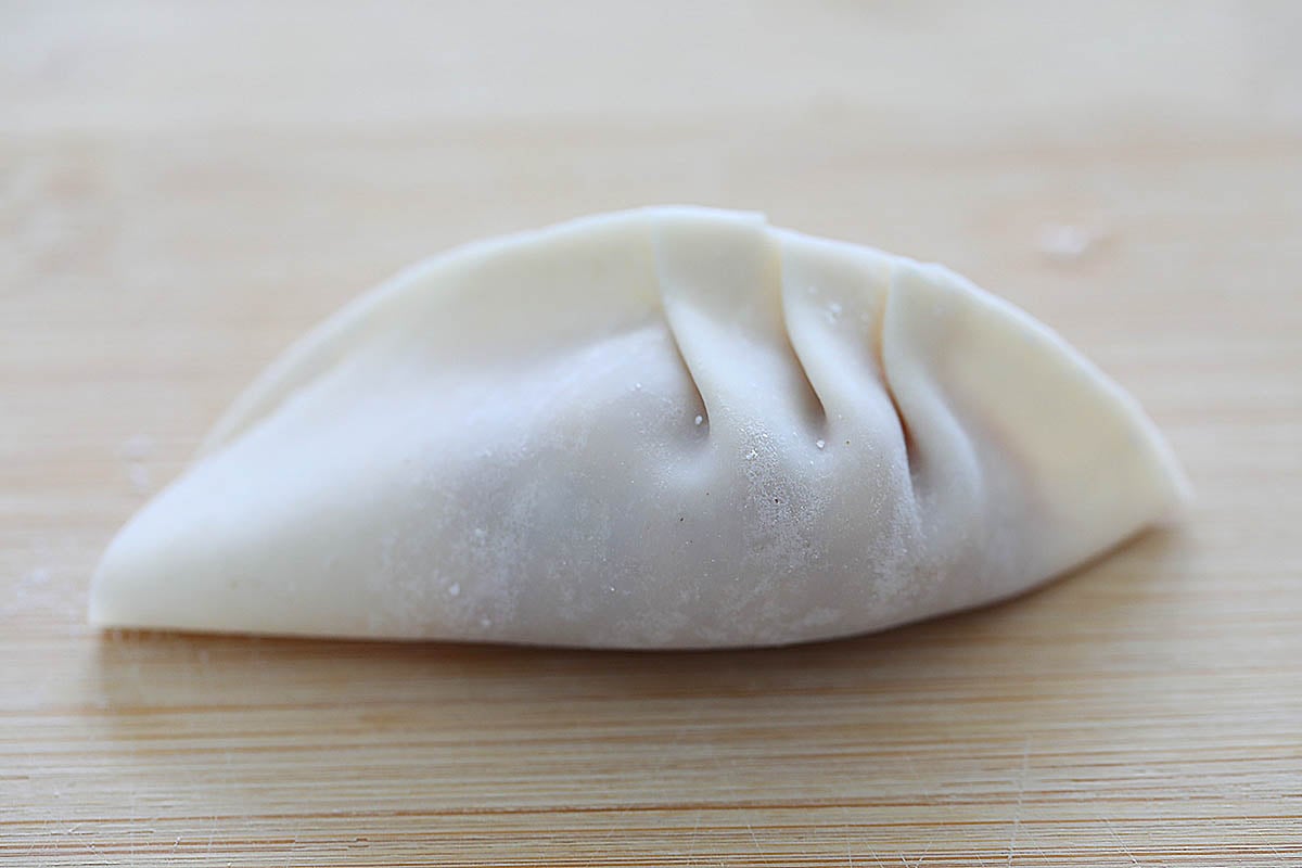 Wrapping dumplings into half moon shape. 