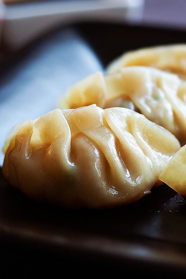 Gyoza served on a plate with a pair of chopsticks.