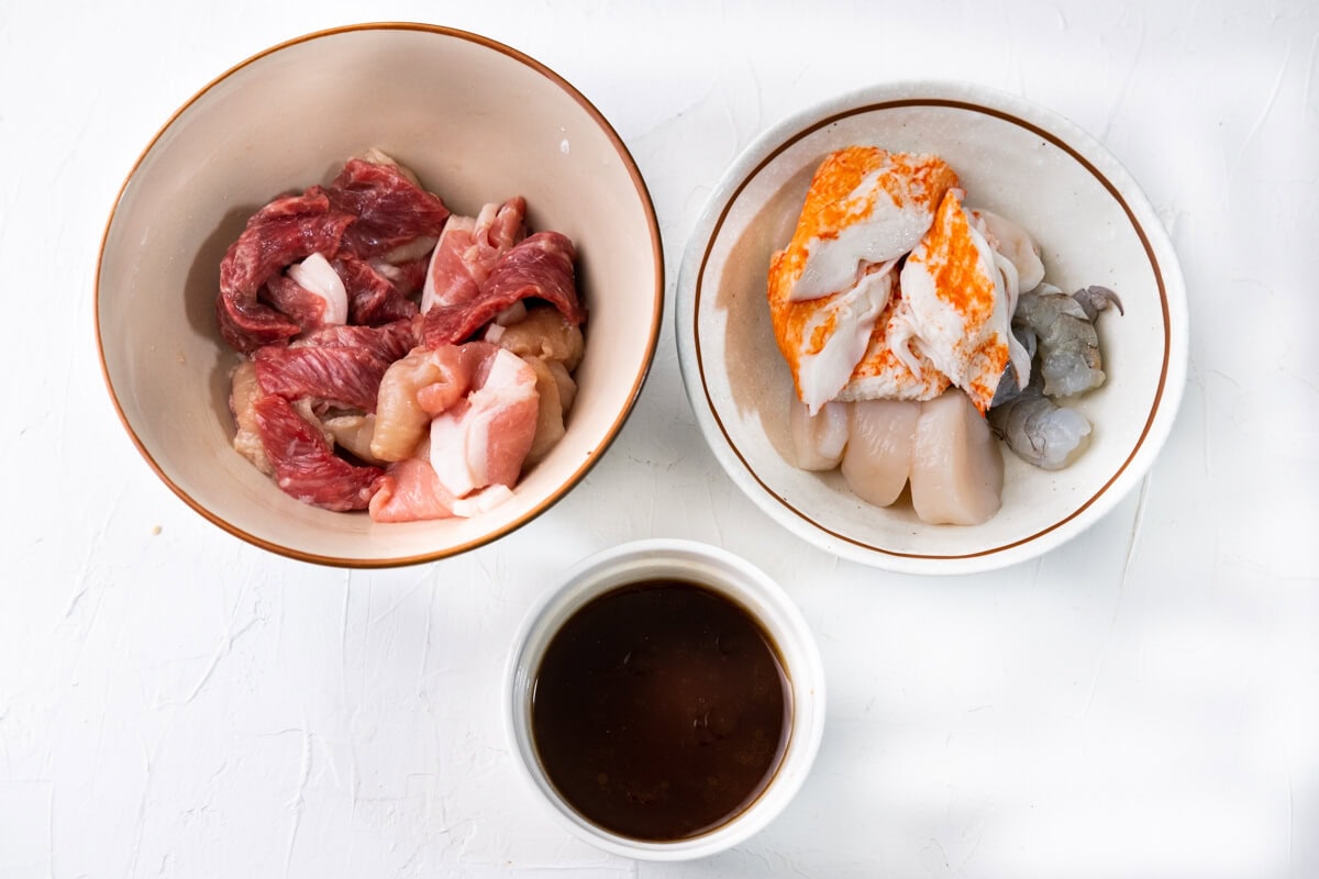 Marinate the beef, pork, chicken, scallop, shrimp, and crab meat in two separate bowls, and mix together all the sauce ingredients in a small bowl. 