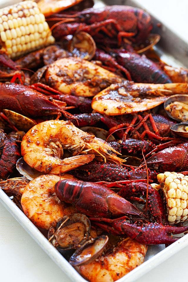 Cooked seafood boil with homemade Cajun butter seasoning in a sheet pan.