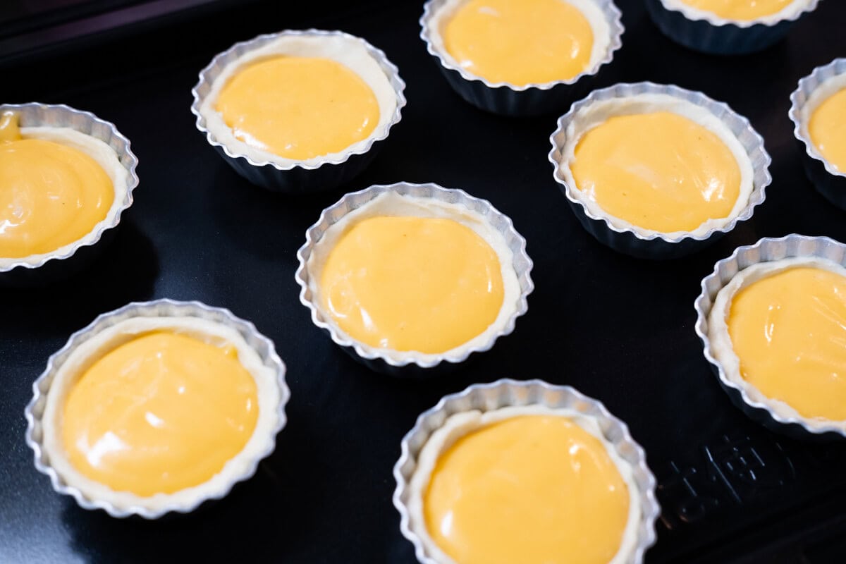 Egg tart filling in pastry shells.  