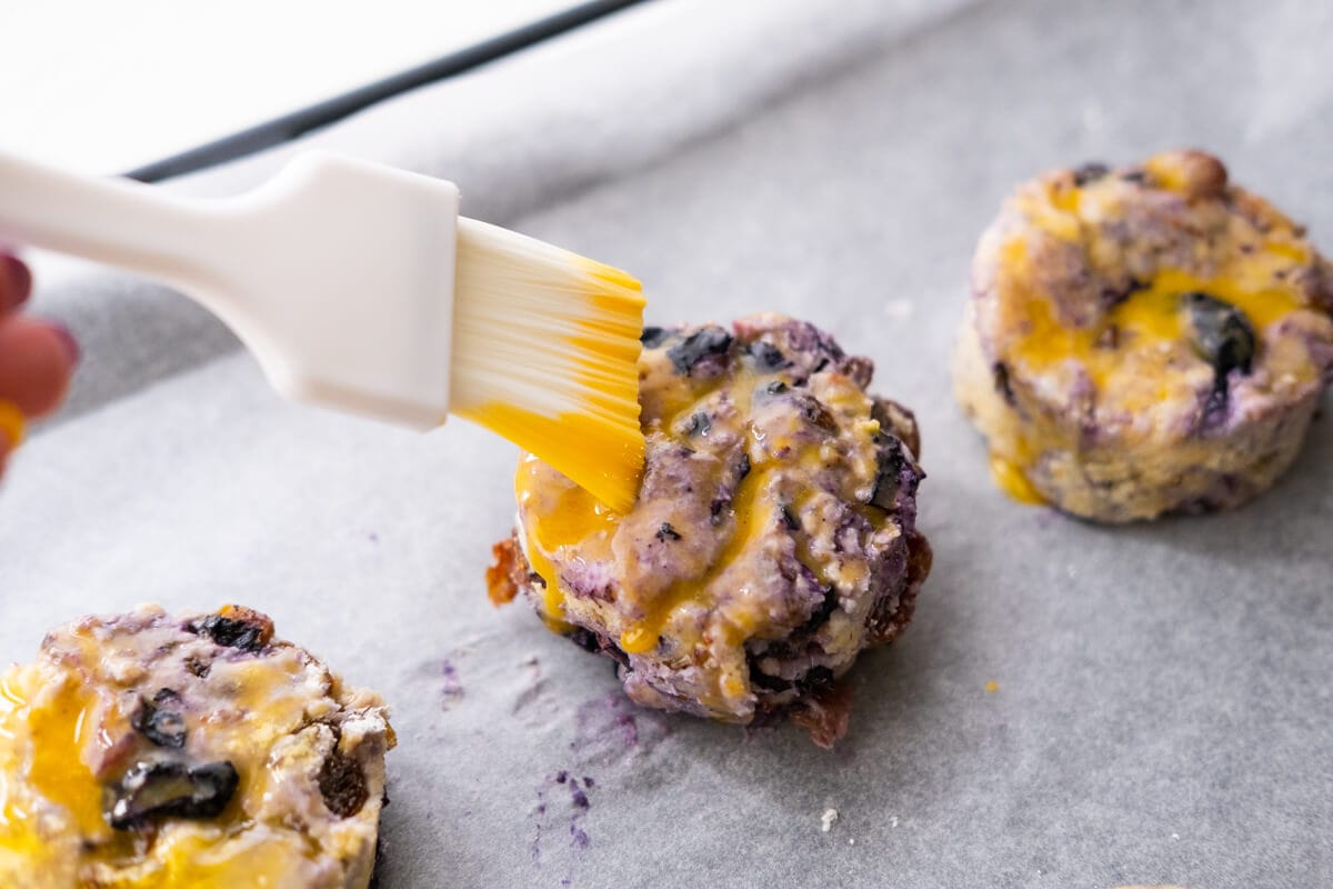 Brushing cut scone dough with egg wash mixture. 