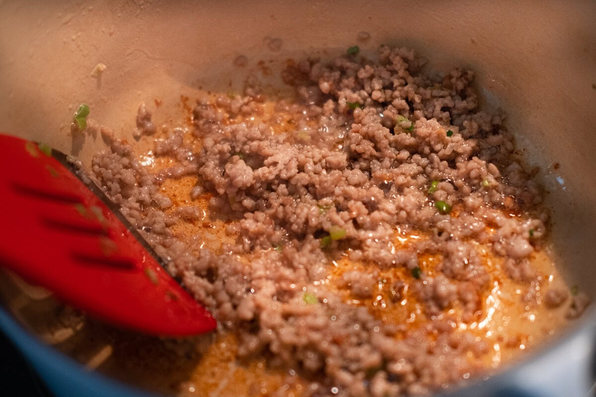 Seasoned ground pork being stir fried in a pan. 