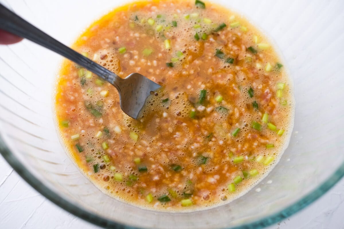 Egg mixture with  ground pork, green onion and seasonings in bowl. 