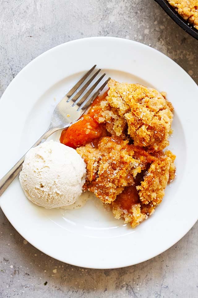 Homemade peach cobbler on a white plate, ready to serve. 