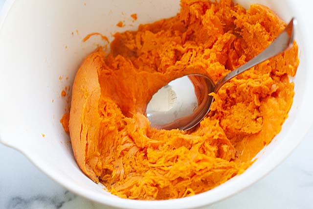 Mash the sweet potatoes using the back of a large spoon.