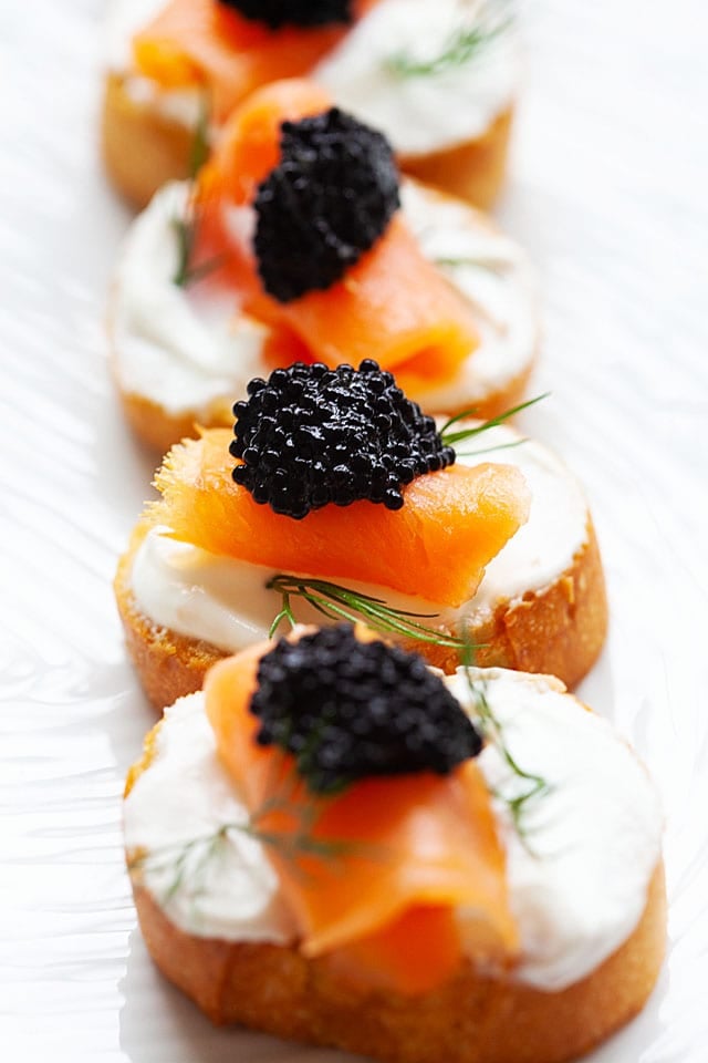 Crostini with sour cream, smoked salmon and caviar topping.