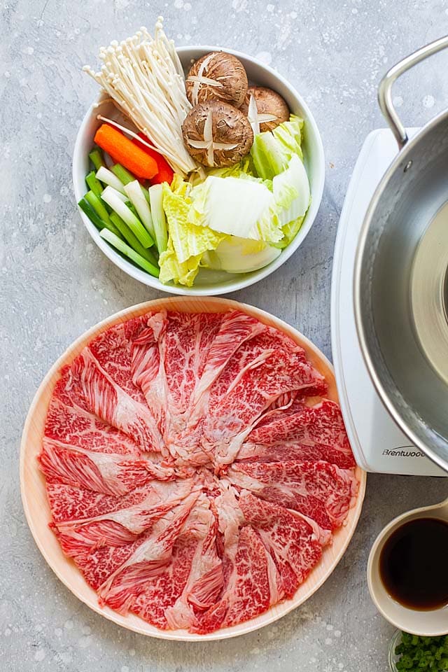 Shabu shabu recipe with beef, vegetables, mushrooms and carrots.