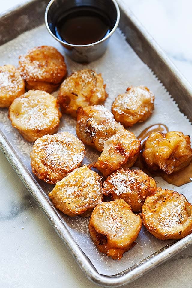 Deep fried bananas with maple syrup on a plate.