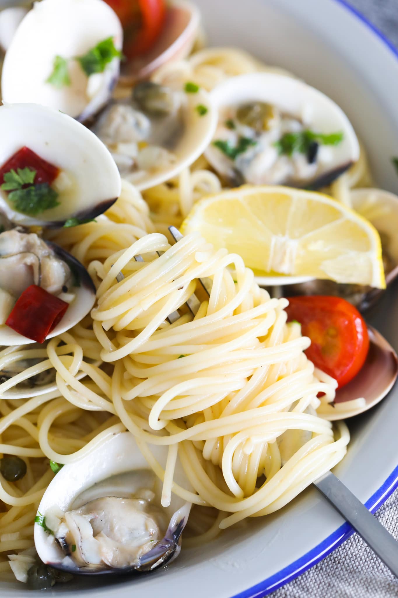 A fork taking a mouthful of Capellini from a plate.