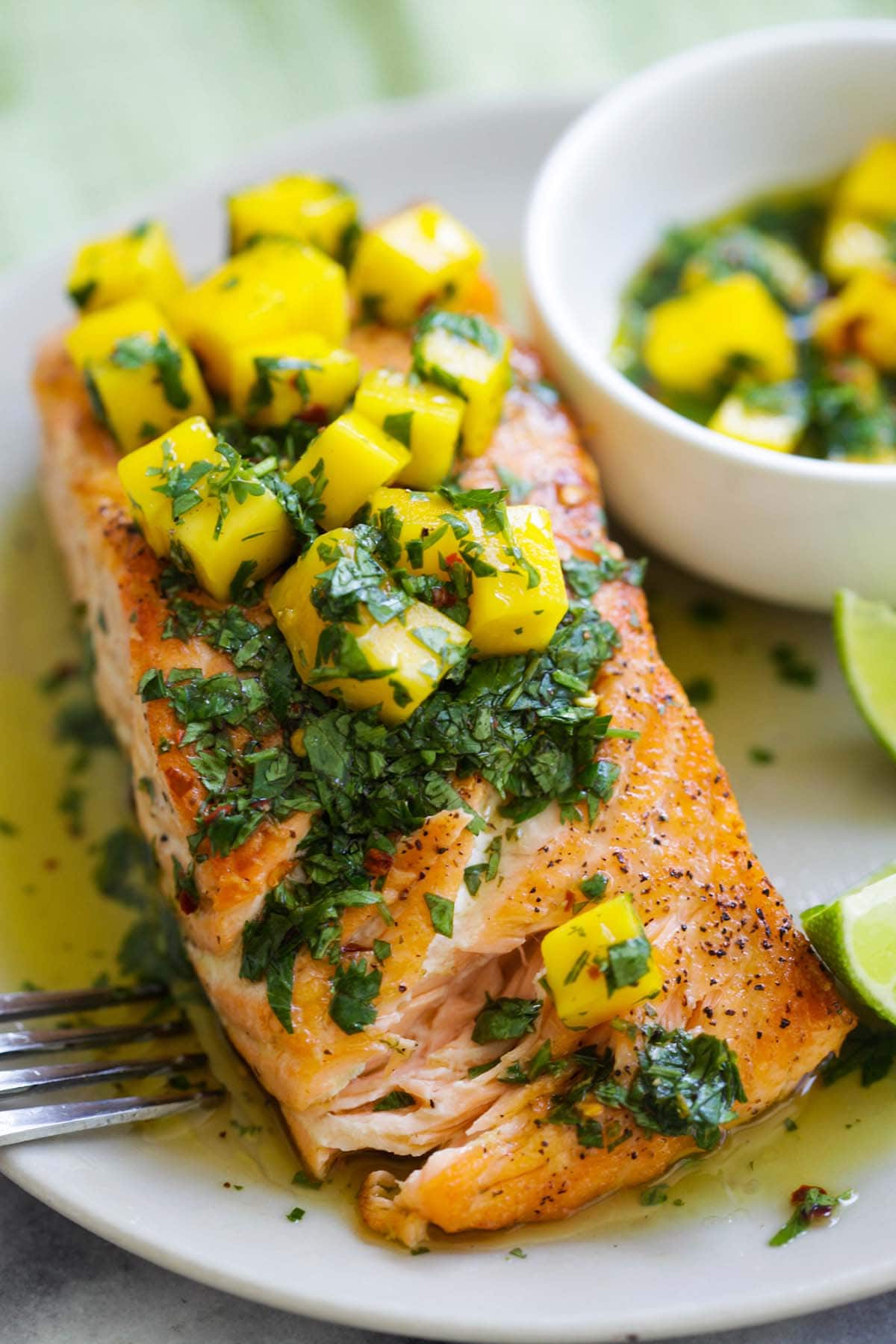 A piece of salmon covered with Chimichurri  sauce with mango, cilantro, parsley, garlic and olive oil.