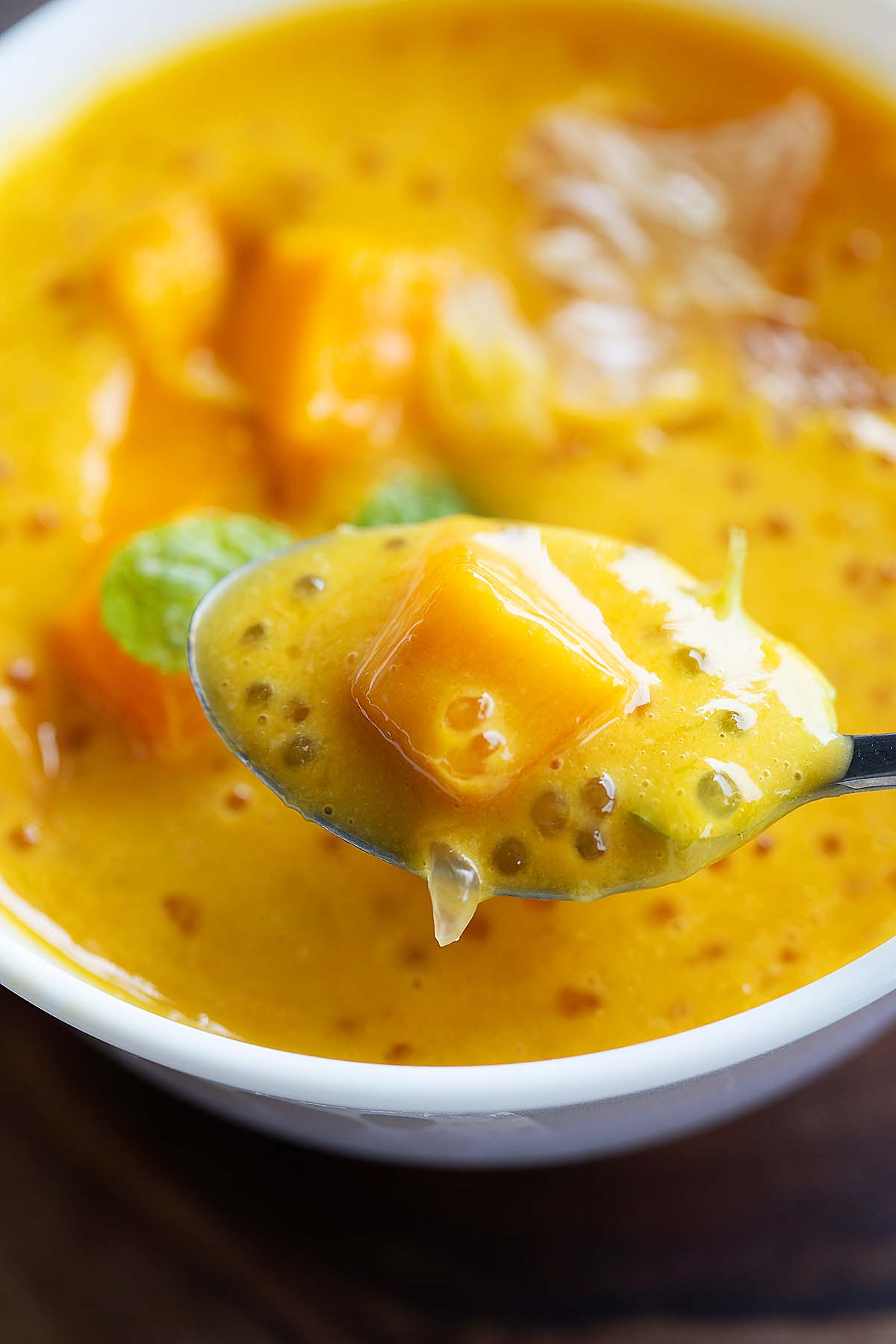 A spoonful scoop of mango dessert featuring mango cubes. 