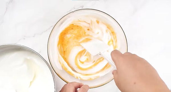 Fold the beaten egg white foam into the egg yolk batter.