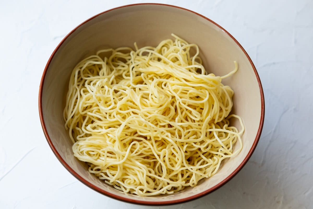 Boil the egg noodles, drain them, and transfer them to a bowl.