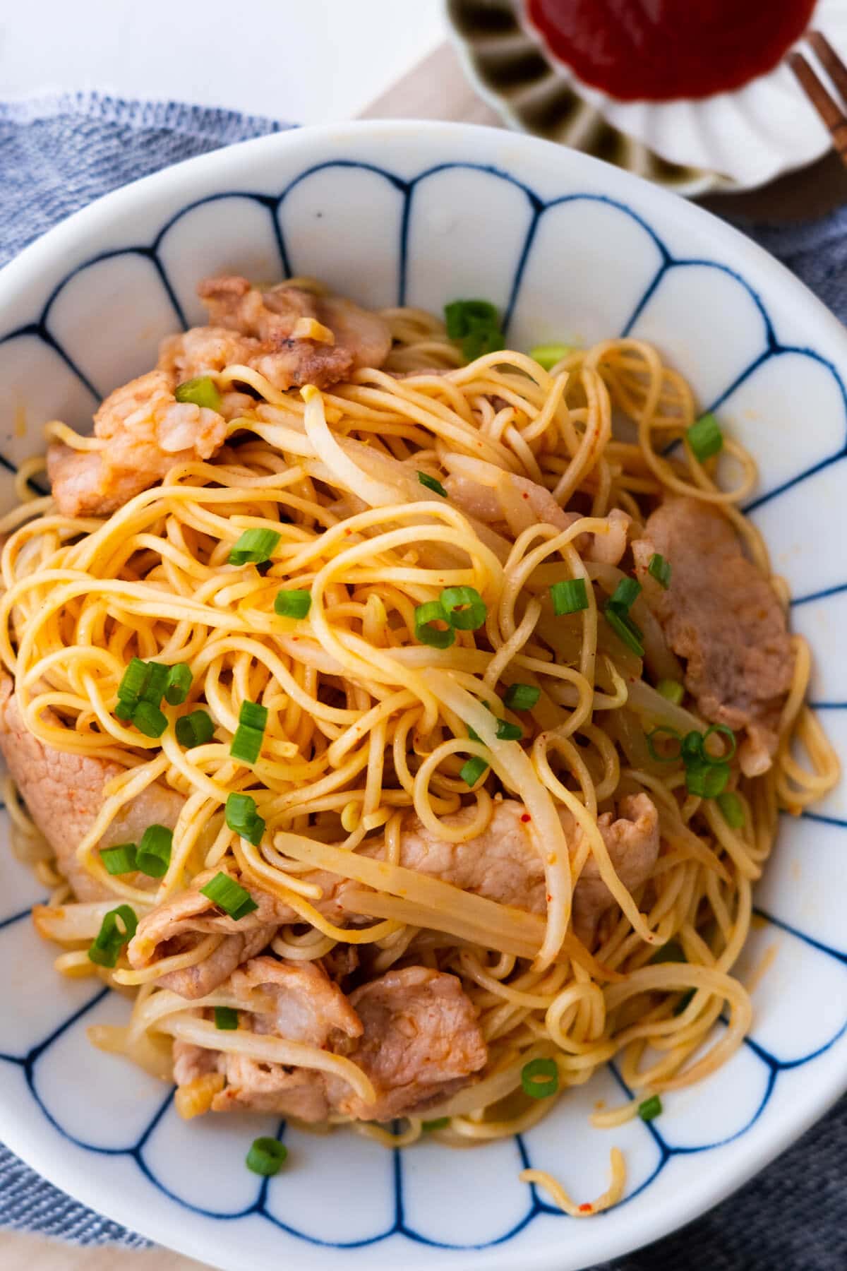 Easy authentic sweet and sour pork on top of stir fry noodles served in a bowl.