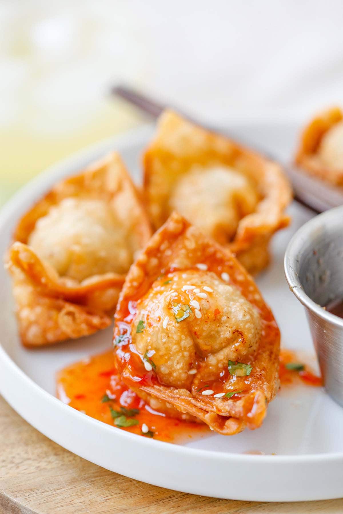 Fried wontons covered in sweet and sour sauce on a plate.