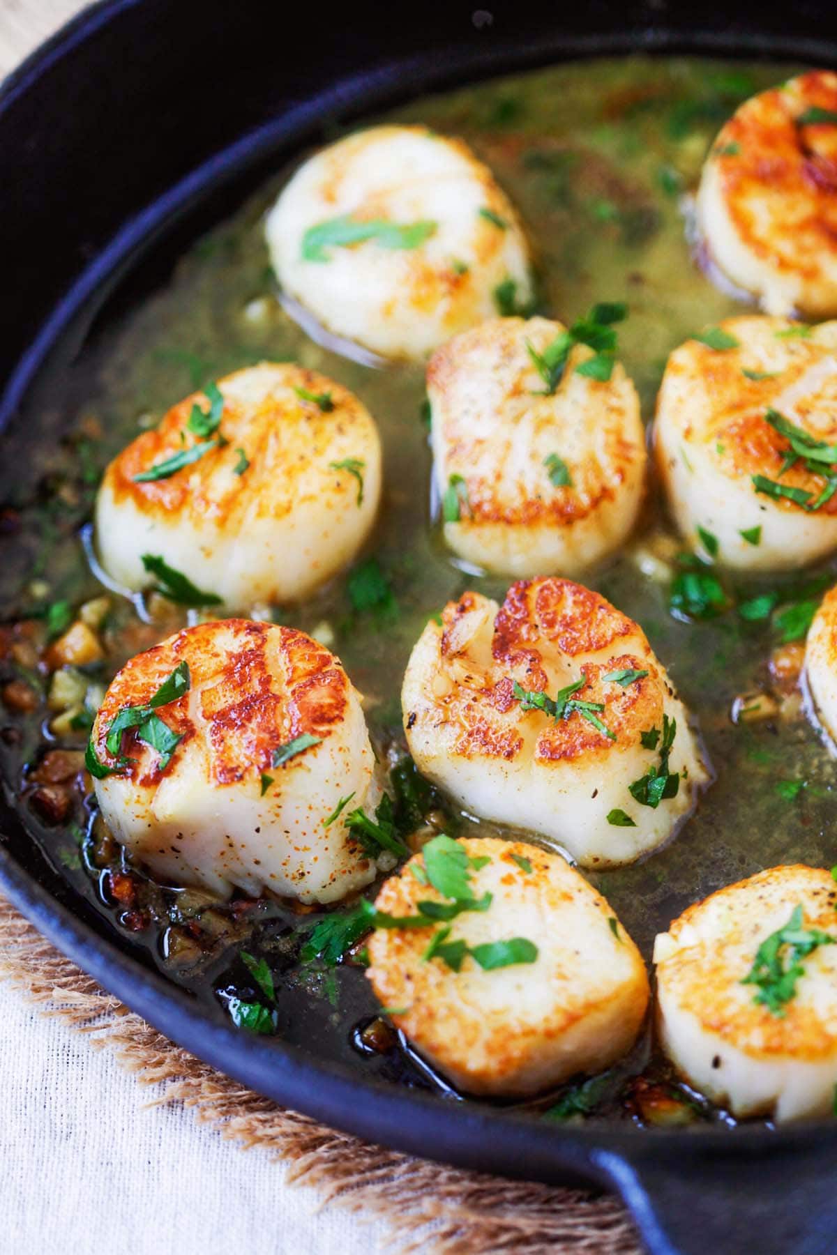 Garlic butter scallops in a cast-iron skillet.