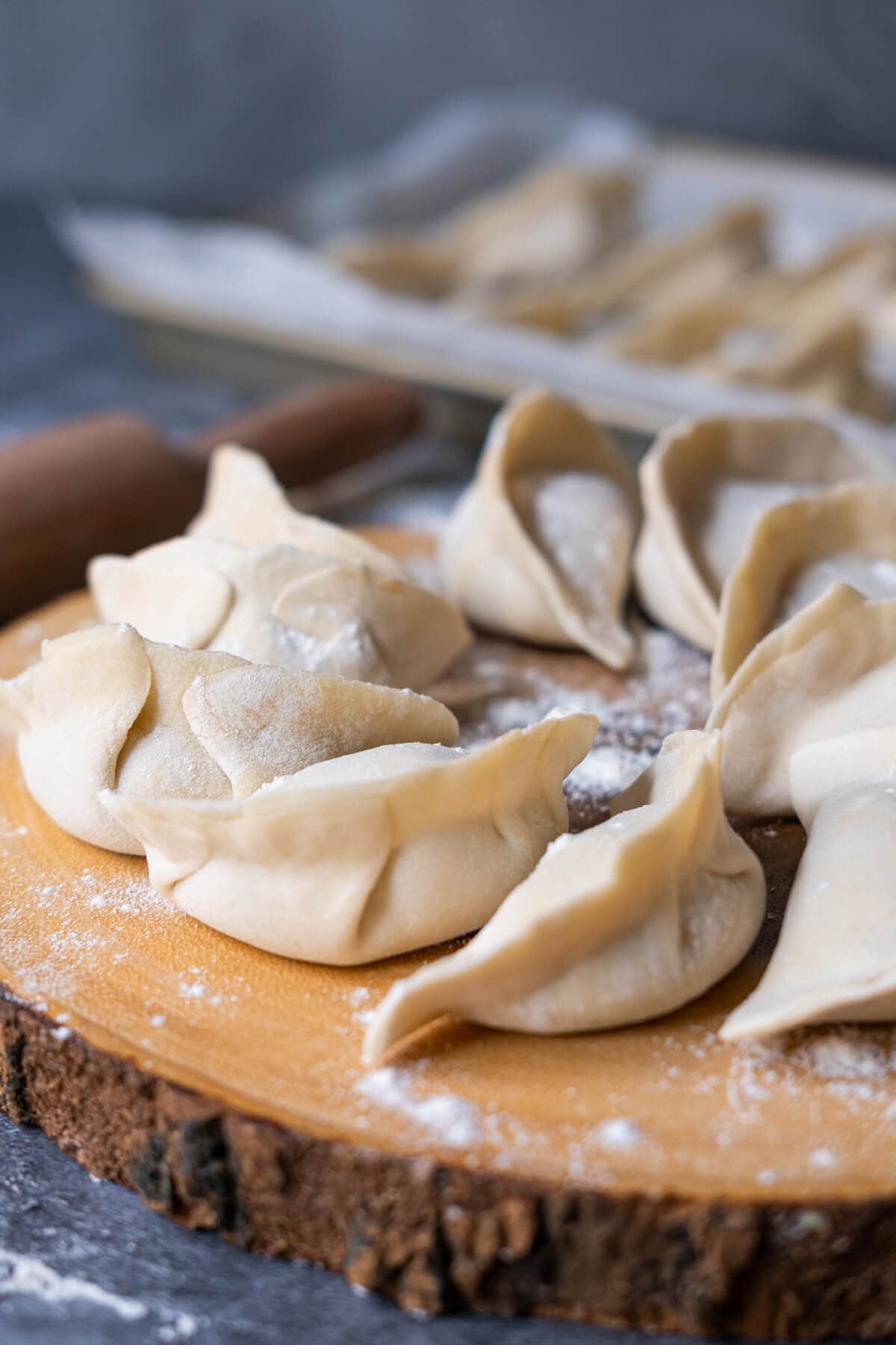 Raw dumplings arranged in a circle on top of a board. 