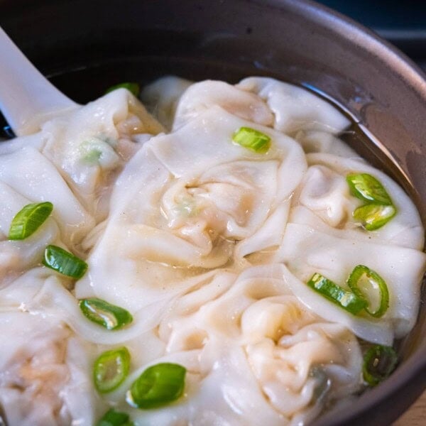 Homemade chicken wonton soup garnished with chopped scallion.