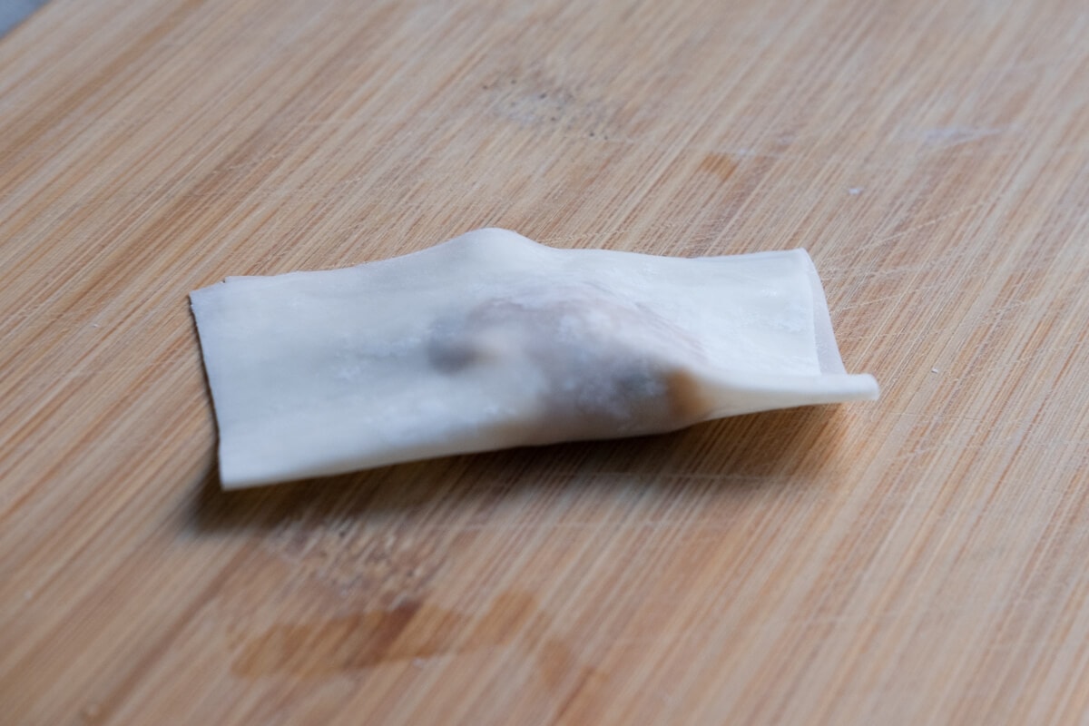 A wonton wrapper folded half over chicken wonton filling.