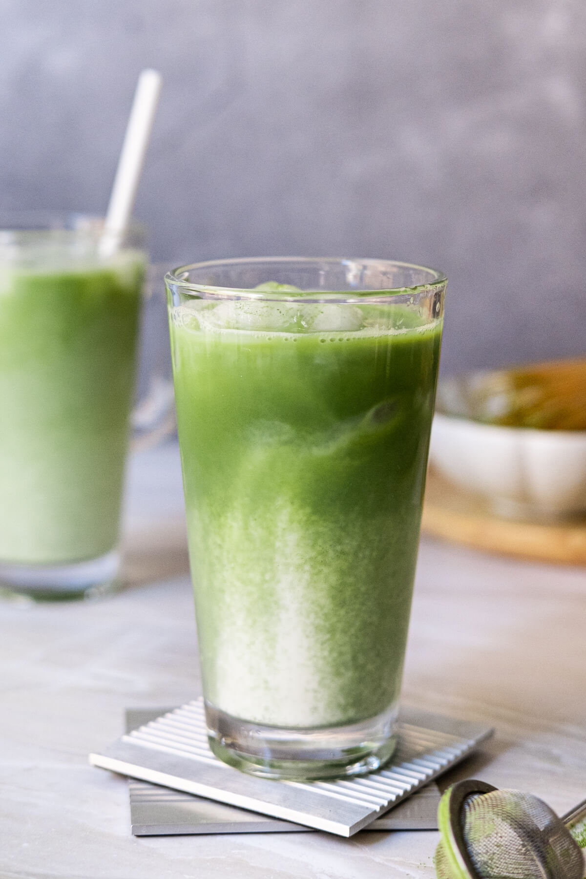 Two glasses of matcha latte with straws, ready to serve.