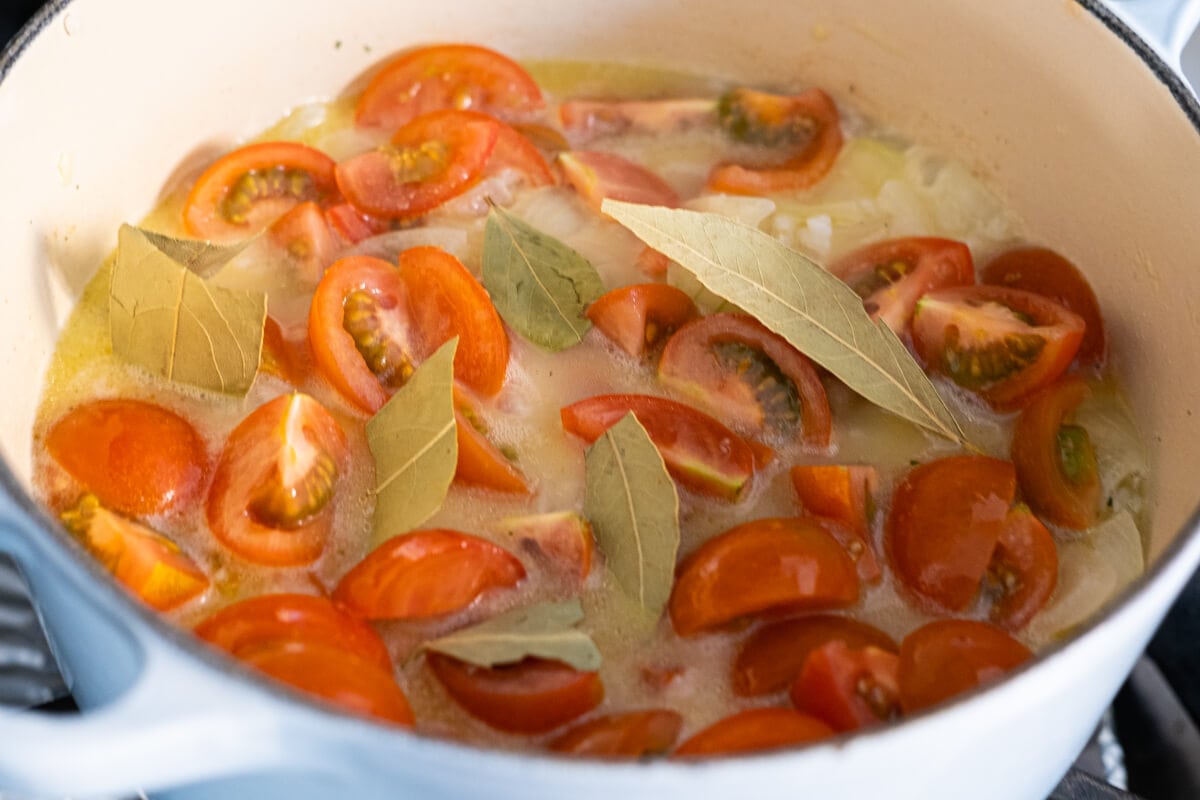 Half sliced tomato boiling with the other ingredients in a pot. 