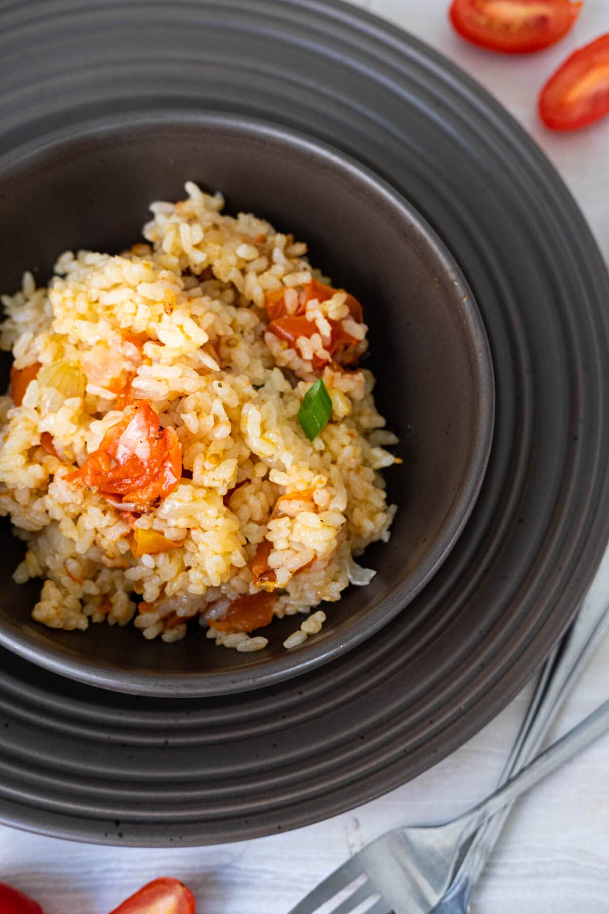 A bowl of golden Spanish rice served in a black bowl. 