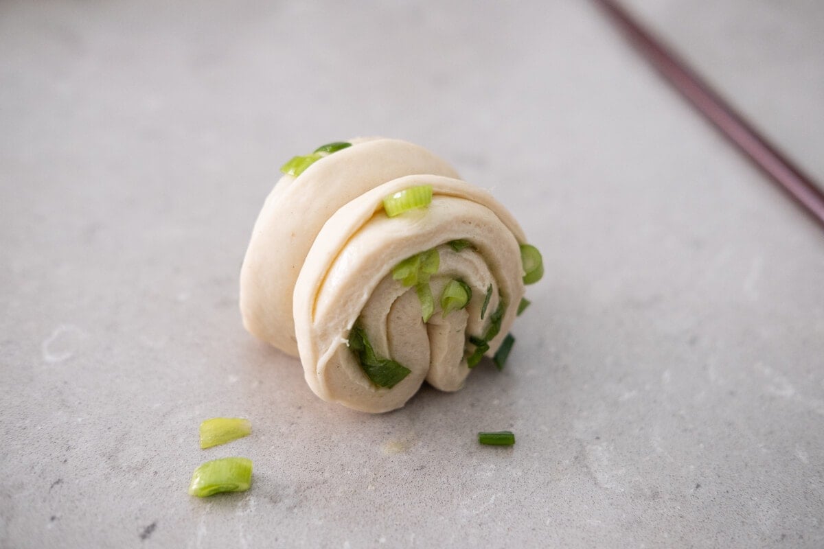 A flower shaped dough sits on the table with one chopstick next to it.