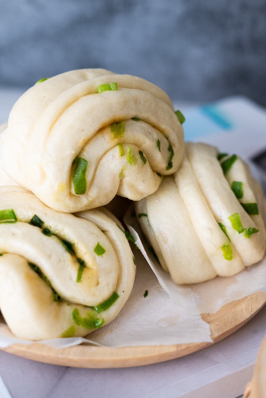 Three buns stack on each other and placed on a parchment lined wooden plate.