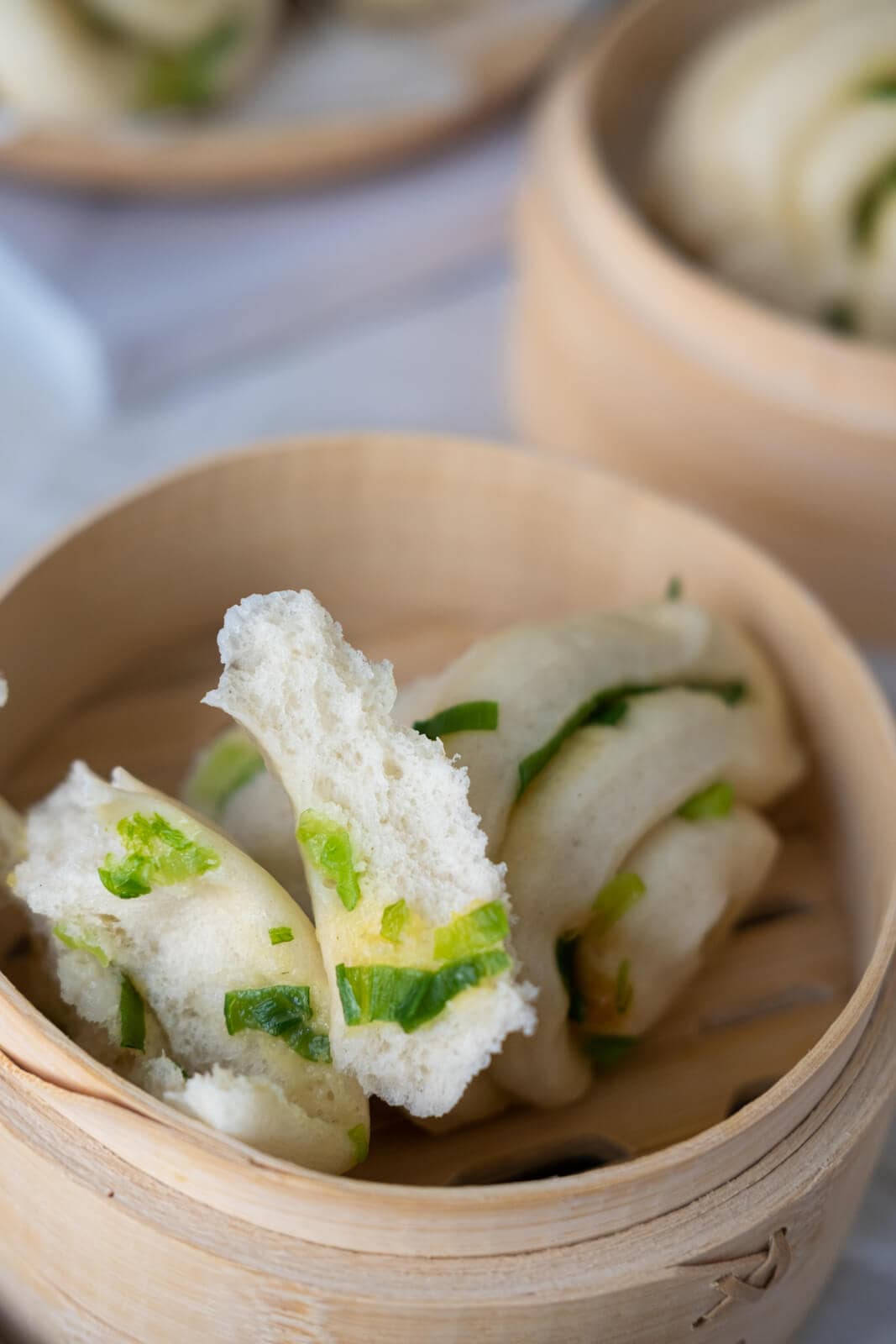 The fluffy scallion bun was pulled apart and sit in a bamboo steamer.